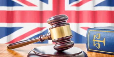 Gerichtshammer und im Hintergrund hängt die Flagge von Großbritannien.
