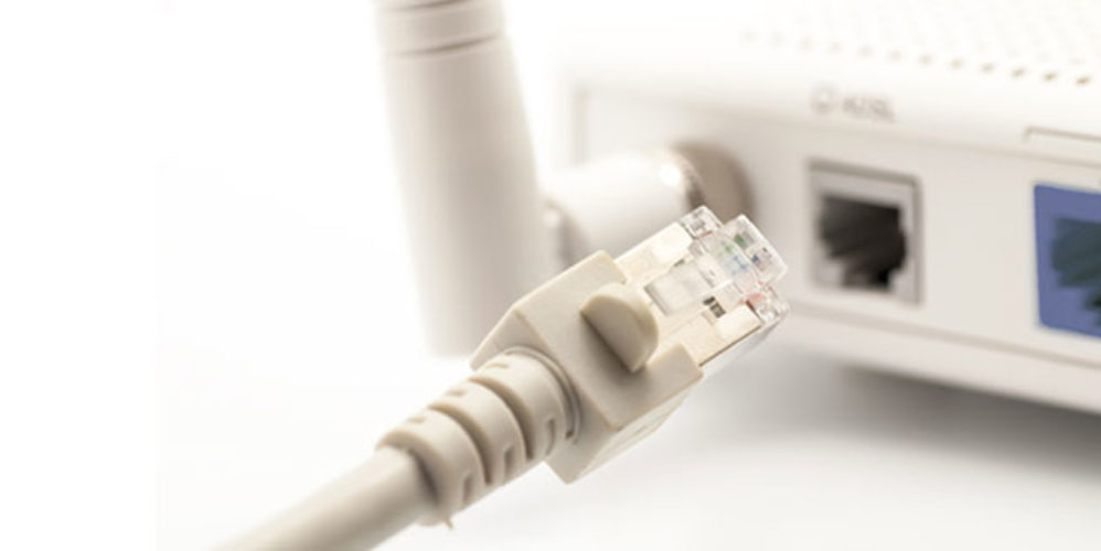 Weißes Kabel wird an einen Router angeschlossen.