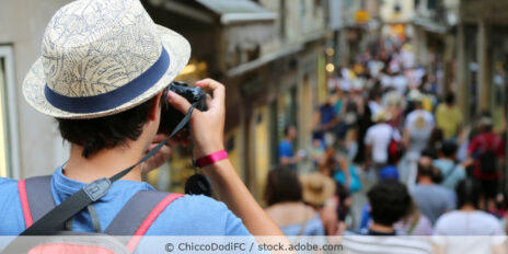 Ein Tourist in Venedig steht am Anfang einer Gasse und fotografiert die Menschen, die dort entlang laufen.