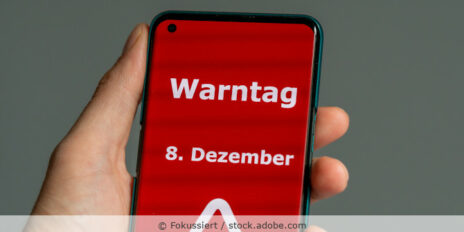 Auf einem Handydisplay steht "Warntag 8. Dezember" in weißer Schrift auf rotem Hintergrund geschrieben.