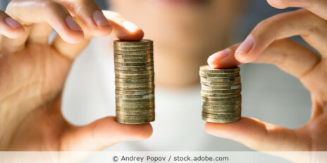 Frau hält zwei ungleich hohe Stapel Münzen in den Händen.