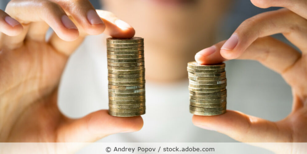 Frau hält zwei ungleich hohe Stapel Münzen in den Händen.