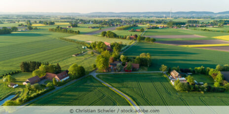 Luftaufnahme einer ländlichen Gegend mit Feldern und Häusern.