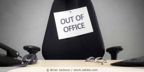 Arbeitsplatz mit Bürostuhl an den ein Zettel mit der Aufschrift „Out of Office“ gepint ist.
